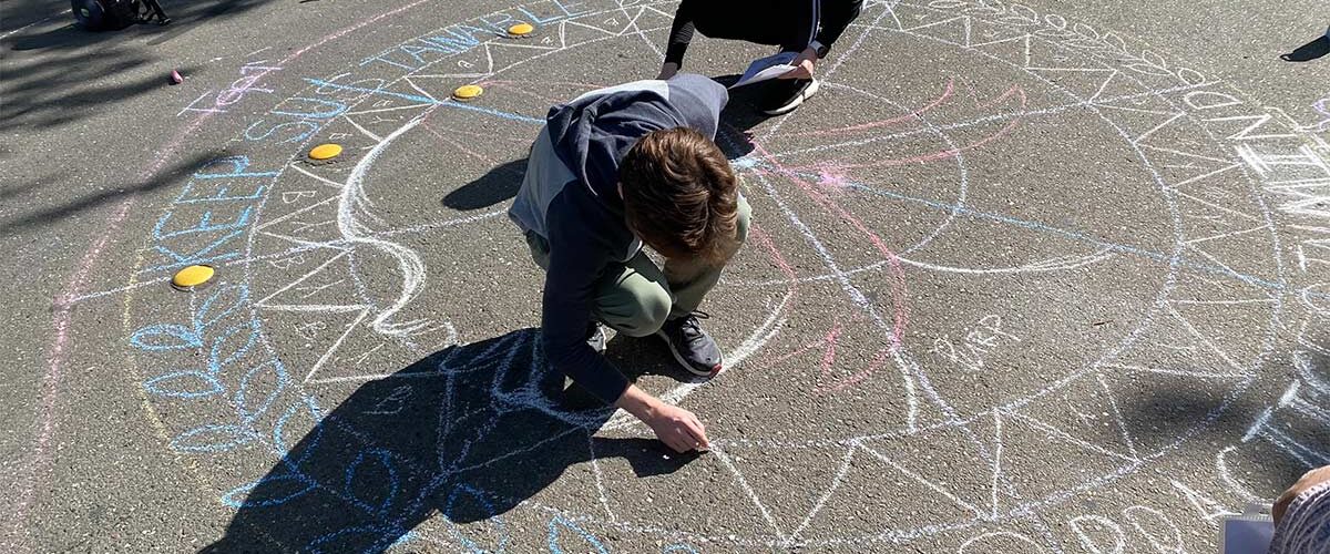 2 students drawing with chalk on the street