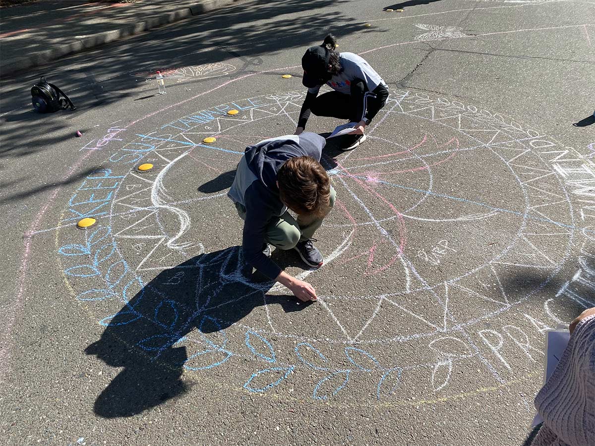 2 students drawing with chalk on the street